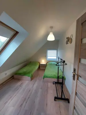 a attic bedroom with two green beds and a window at Ważka - apartament 6 osobowy in Krzeszów
