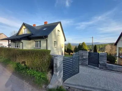 a white house with a black roof and a fence at Ważka - apartament 6 osobowy in Krzeszów