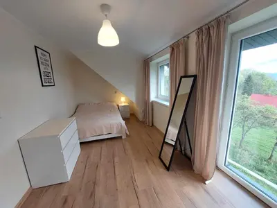 a bedroom with a bed and a mirror and a window at Ważka - apartament 6 osobowy in Krzeszów