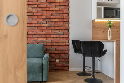 a living room with a brick wall and a chair at Apartament Bulwary 36 in Oświęcim