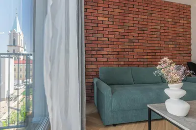 a living room with a green couch and a brick wall at Apartament Bulwary 36 in Oświęcim
