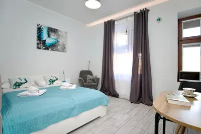 a bedroom with a blue bed and a table and a chair at K12 Apartments in Kraków