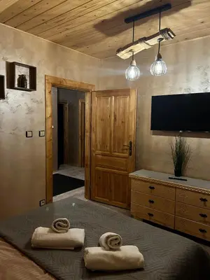 a bedroom with two towels on a bed with a flat screen tv at Leśne Zacisze & Spa na wyłączność in Lubień
