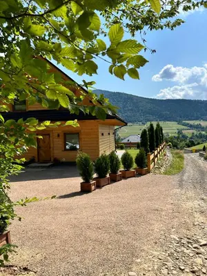 a building with potted plants on the side of a road at Leśne Zacisze & Spa na wyłączność in Lubień