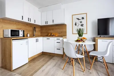 a kitchen with white cabinets and a table and chairs at Aleja 69 Premium in Kraków