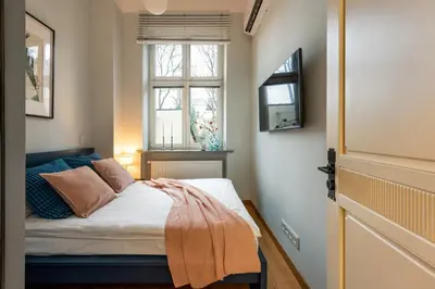 a small bedroom with a bed and a window at Pastell Apartments in Kraków