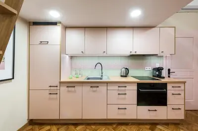 a kitchen with white cabinets and a sink at Pastell Apartments in Kraków
