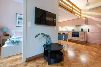 a bedroom and a living room with a bed and a table at Pastell Apartments in Kraków