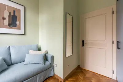 a living room with a blue couch and a mirror at Pastell Apartments in Kraków