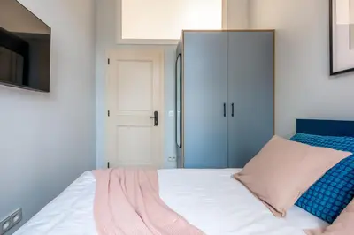 a bedroom with a white bed and a closet at Pastell Apartments in Kraków