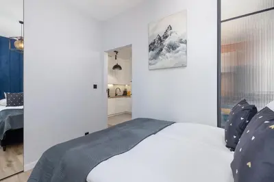 a white bedroom with a bed and a kitchen at Lux Kraków Apartment with Parking & AC just 1,5 km from Main Square by Renters Prestige in Kraków