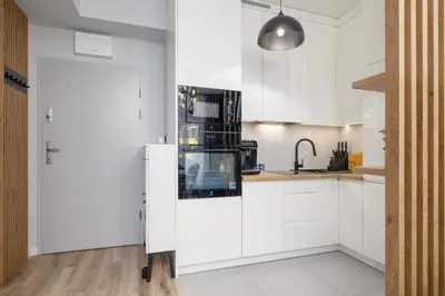 a kitchen with white cabinets and a black refrigerator at Lux Kraków Apartment with Parking & AC just 1,5 km from Main Square by Renters Prestige in Kraków