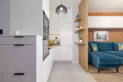 a living room with a blue couch and a kitchen at Lux Kraków Apartment with Parking & AC just 1,5 km from Main Square by Renters Prestige in Kraków