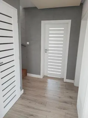an empty room with white doors and wooden floors at Stylowy Apartament z ogrodem in Gorenice