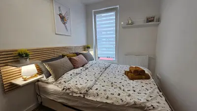 a bedroom with a bed with a teddy bear on it at Apartamenty FIGARETTI in Kraków