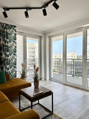 a living room with a couch and large windows at Apartamenty FIGARETTI in Kraków