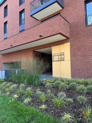 a red brick building with a door and some plants at Forum Apartment in Kraków