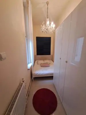 a small room with a bed and a chandelier at Szymborska Stradomska 5 in Kraków