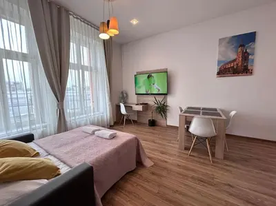 a bedroom with a bed and a desk and a television at Bosacka Street - Apartament B31 in Kraków