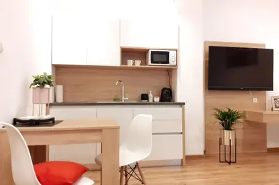 a living room with a table and a kitchen with a tv at Bosacka Street - Apartament B26 in Kraków