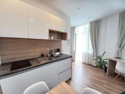 a kitchen with a sink and a counter with chairs at Cozy Apartment - B38 in Kraków