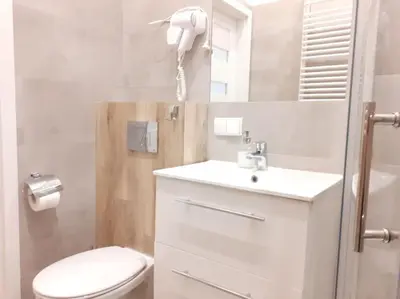 a white bathroom with a toilet and a sink at Cozy Apartment - B38 in Kraków