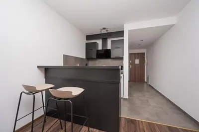 a kitchen with a black counter and stools in a room at RentPlanet - Apartament Mireckiego in Kraków