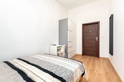 a white bedroom with a bed and a desk at Kochanowskiego 23 Apartament in Kraków