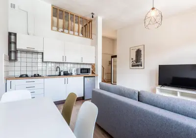 a living room with a blue couch and a kitchen at Kochanowskiego 23 Apartament in Kraków