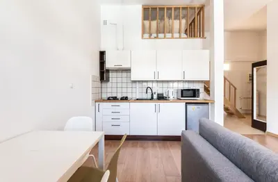 a kitchen with white cabinets and a table and a couch at Kochanowskiego 23 Apartament in Kraków