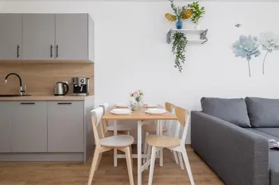 a kitchen with a table and chairs next to a couch at Nowoczesny Apartament w Krakowie z Klimatyzacją i Parkingiem by Noclegi Renters in Kraków