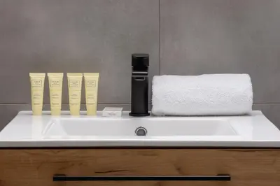 a bathroom sink with a black and yellow bottle on it at Nowoczesny Apartament w Krakowie z Klimatyzacją i Parkingiem by Noclegi Renters in Kraków