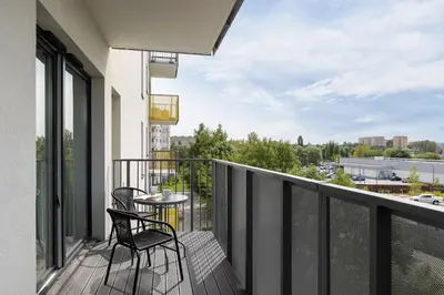a balcony with two chairs and a table at Nowoczesny Apartament w Krakowie z Klimatyzacją i Parkingiem by Noclegi Renters in Kraków