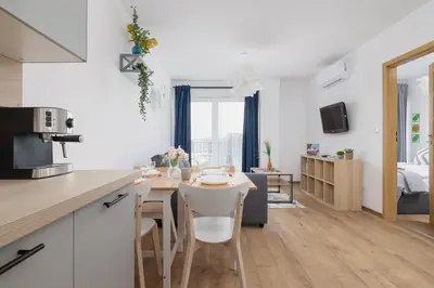 a kitchen and living room with a table and chairs at Nowoczesny Apartament w Krakowie z Klimatyzacją i Parkingiem by Noclegi Renters in Kraków