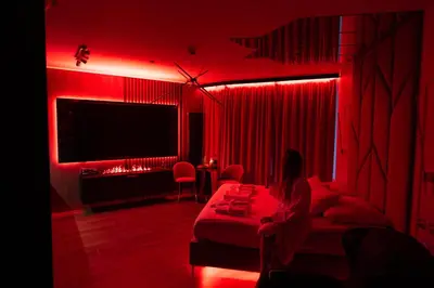 a woman sitting on a bed in a red room at Apartament z jacuzzi, Wiślane Tarasy in Kraków