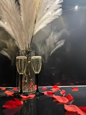 two glasses of champagne on a table with red flowers at Apartament z jacuzzi, Wiślane Tarasy in Kraków
