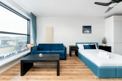 a living room with a blue couch and a bed at Wiślane Tarasy 2 0 Blue Studio by BookingHost in Kraków