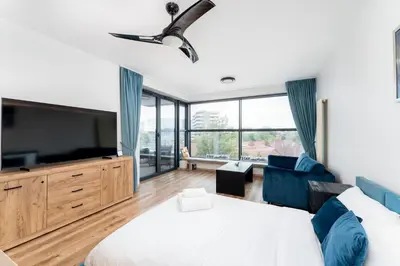 a bedroom with a bed and a flat screen tv at Wiślane Tarasy 2 0 Blue Studio by BookingHost in Kraków