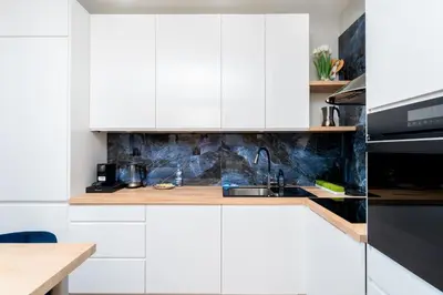 a kitchen with white cabinets and a sink at Wiślane Tarasy 2 0 Blue Studio by BookingHost in Kraków
