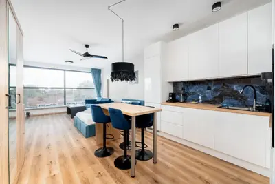 a kitchen with white cabinets and a table with blue chairs at Wiślane Tarasy 2 0 Blue Studio by BookingHost in Kraków