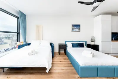 two beds in a room with a blue couch at Wiślane Tarasy 2 0 Blue Studio by BookingHost in Kraków