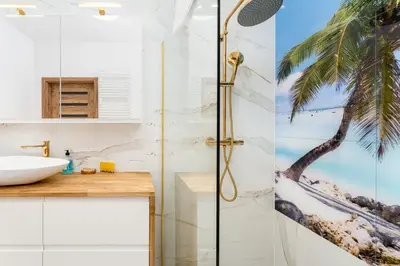 a bathroom with a shower with a palm tree mural at Wiślane Tarasy 2 0 Blue Studio by BookingHost in Kraków