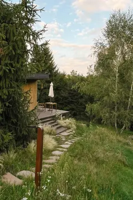 a patio with a table and an umbrella on a deck at hOMM domek nad jeziorem in Stryszów