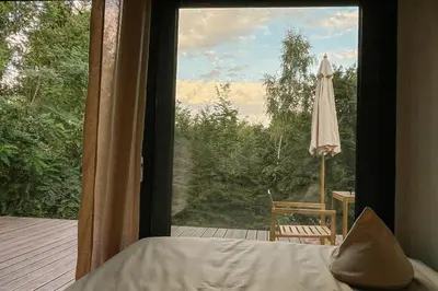 a bedroom with a large window looking out onto a deck at hOMM domek nad jeziorem in Stryszów