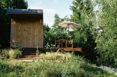 a chair and an umbrella in front of a building at hOMM domek nad jeziorem in Stryszów