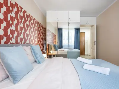 a bedroom with a large white bed with blue pillows at Rewers apartment - Świętokrzyska St in Kraków
