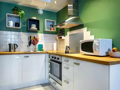 a kitchen with white cabinets and green walls at Rewers apartment - Świętokrzyska St in Kraków