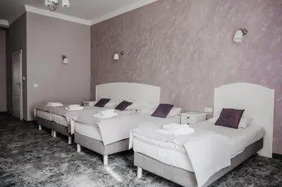 a room with three beds with white sheets and purple pillows at Pałac Lacon in Kazimierza Wielka