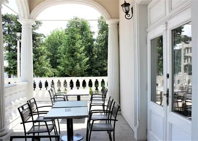 a porch with tables and chairs and a large window at Pałac Lacon in Kazimierza Wielka