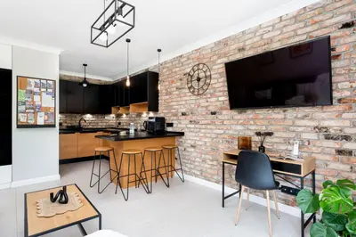 a brick wall in a kitchen with bar stools at Malila Premium Apartments Cracow Tauron Arena Lema 15 in Kraków